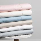 Stack of folded pastel-colored bed sheets on a gray background