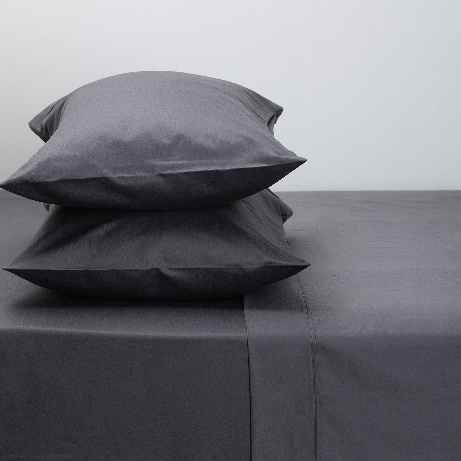 Gray bedding set with two pillows on a plain background