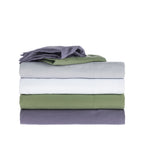 Stack of folded bed sheets in green, white, and gray on a white background