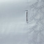 Close up of the Gracious Living Celine Embroidery Sheet Set in Blue, showing the embroidered leaf cuff and brand label.