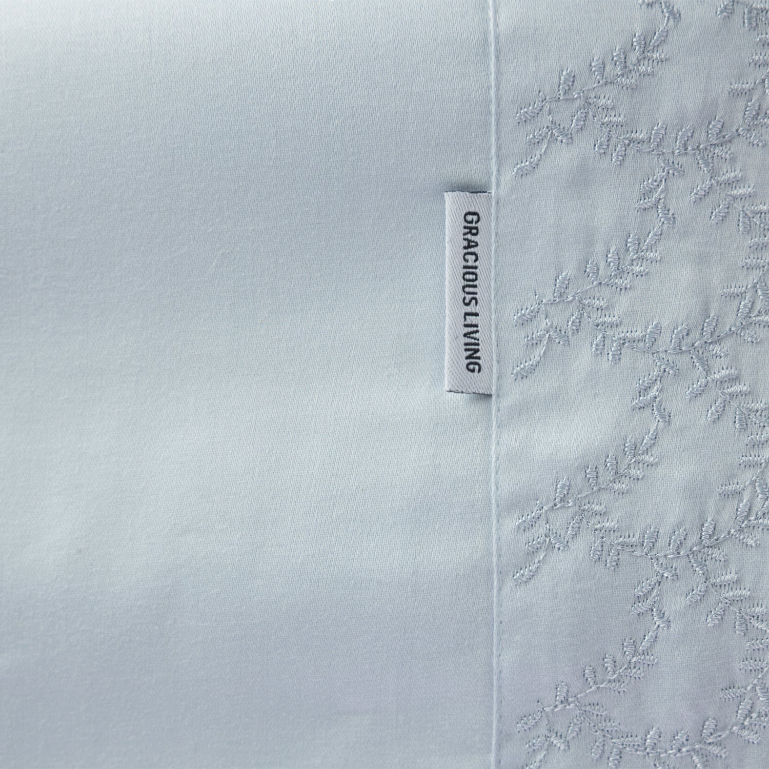 Close up of the Gracious Living Celine Embroidery Sheet Set in Blue, showing the embroidered leaf cuff and brand label.