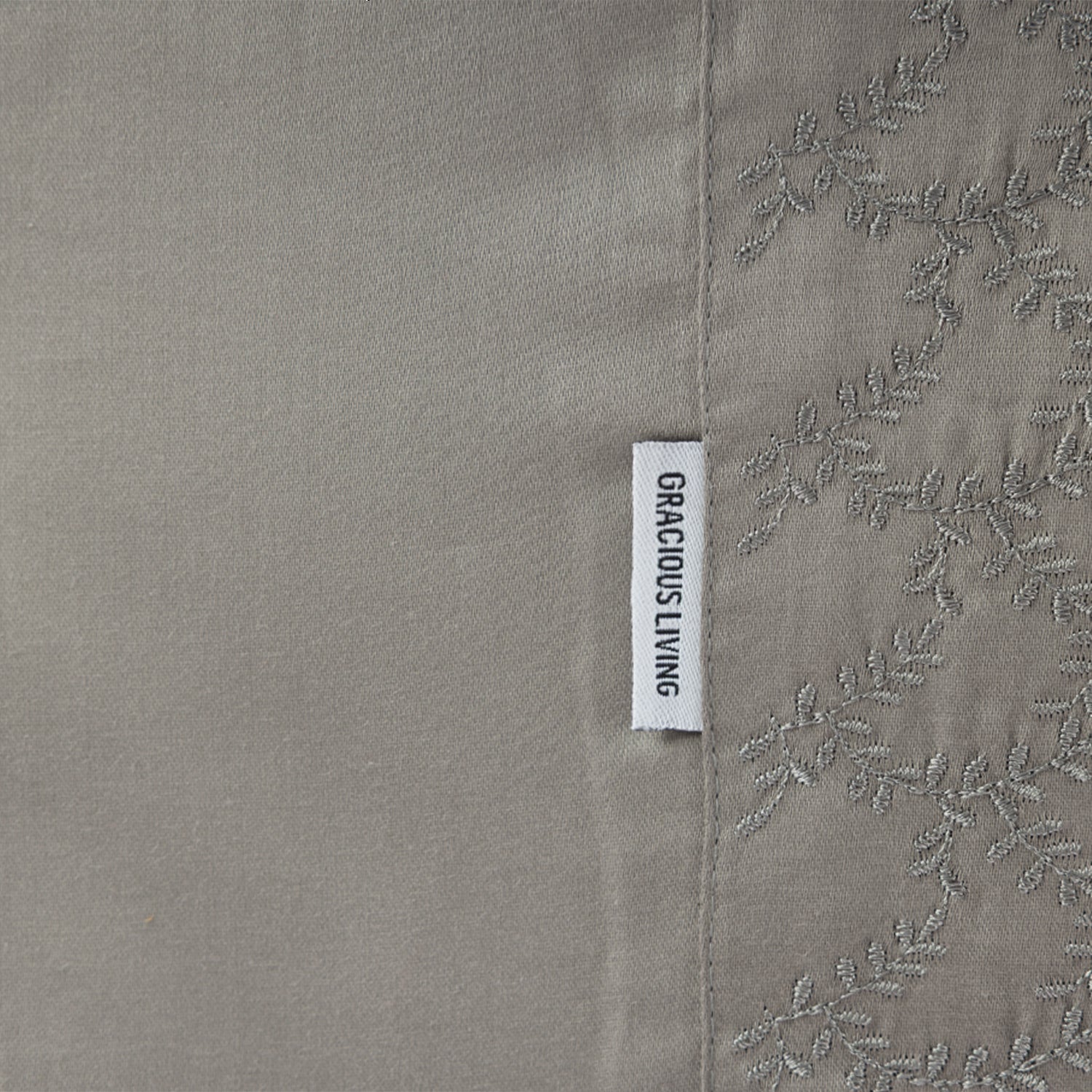 Close up of the Gracious Living Celine Embroidery Sheet Set in Stone, showing the embroidered leaf cuff and brand label.