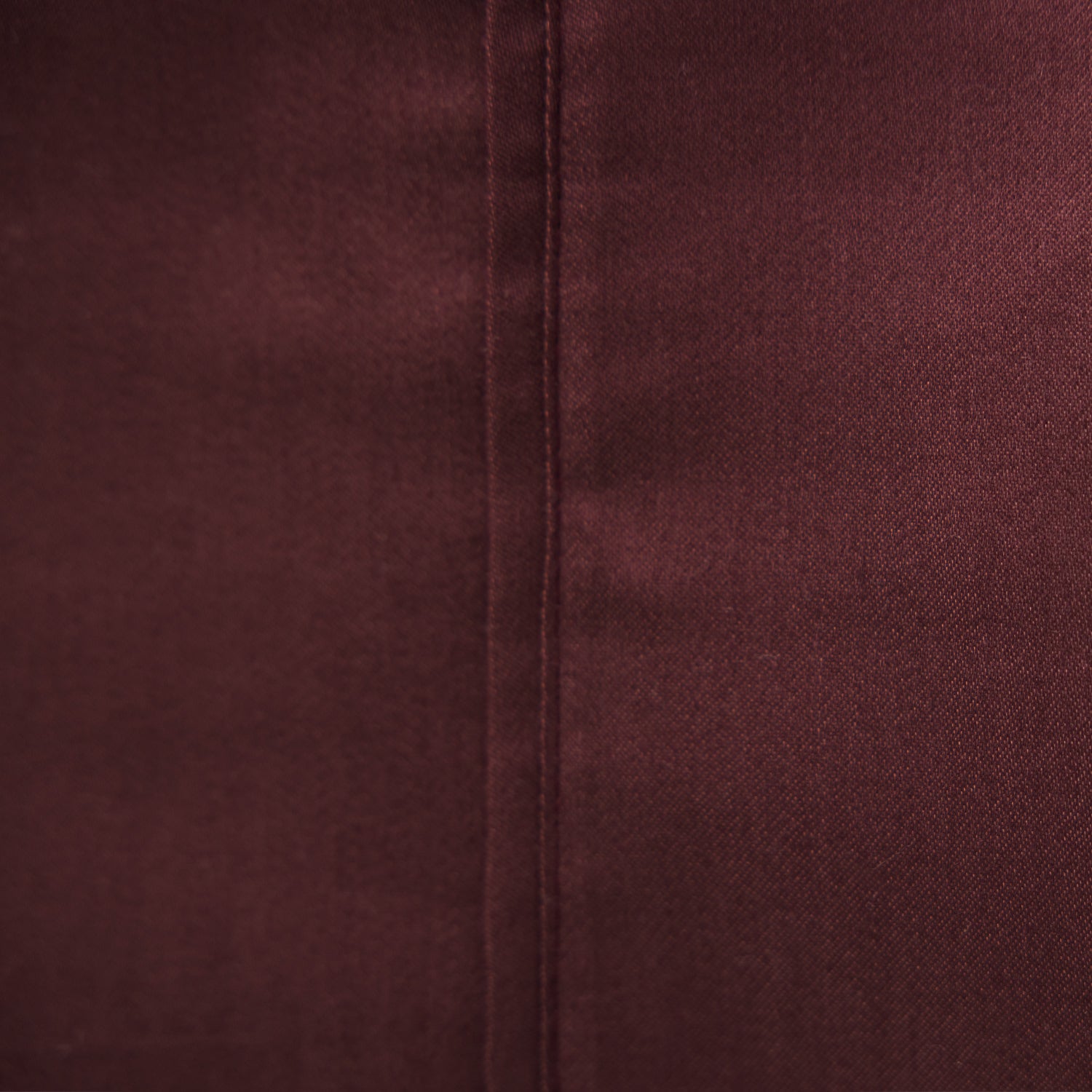 Close-up of the Solace Satin Sheet Set in Berry, showing the rich burgundy-toned satin-look fabric and stitched seam.
