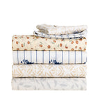 Folded Pure & Simple printed sheet sets stacked together, featuring Nova Blue, Finn Natural, Emma Silver and Lucy Floral designs.