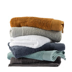 Stack of Egyptian cotton bath towels in Marigold, Silver, White, Diesel Blue, Marine and Charcoal colourways.