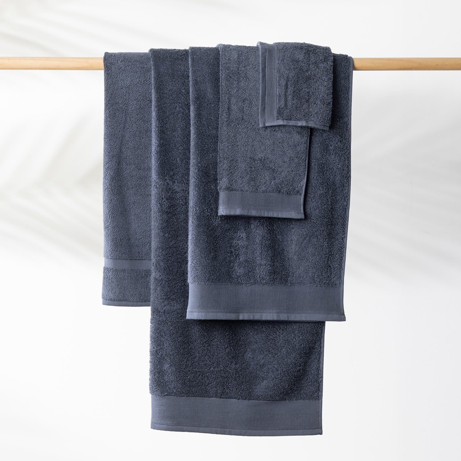 Diesel Blue Egyptian cotton towel collection including a bath sheet, bath towel and hand towel hanging on a wooden towel rail.