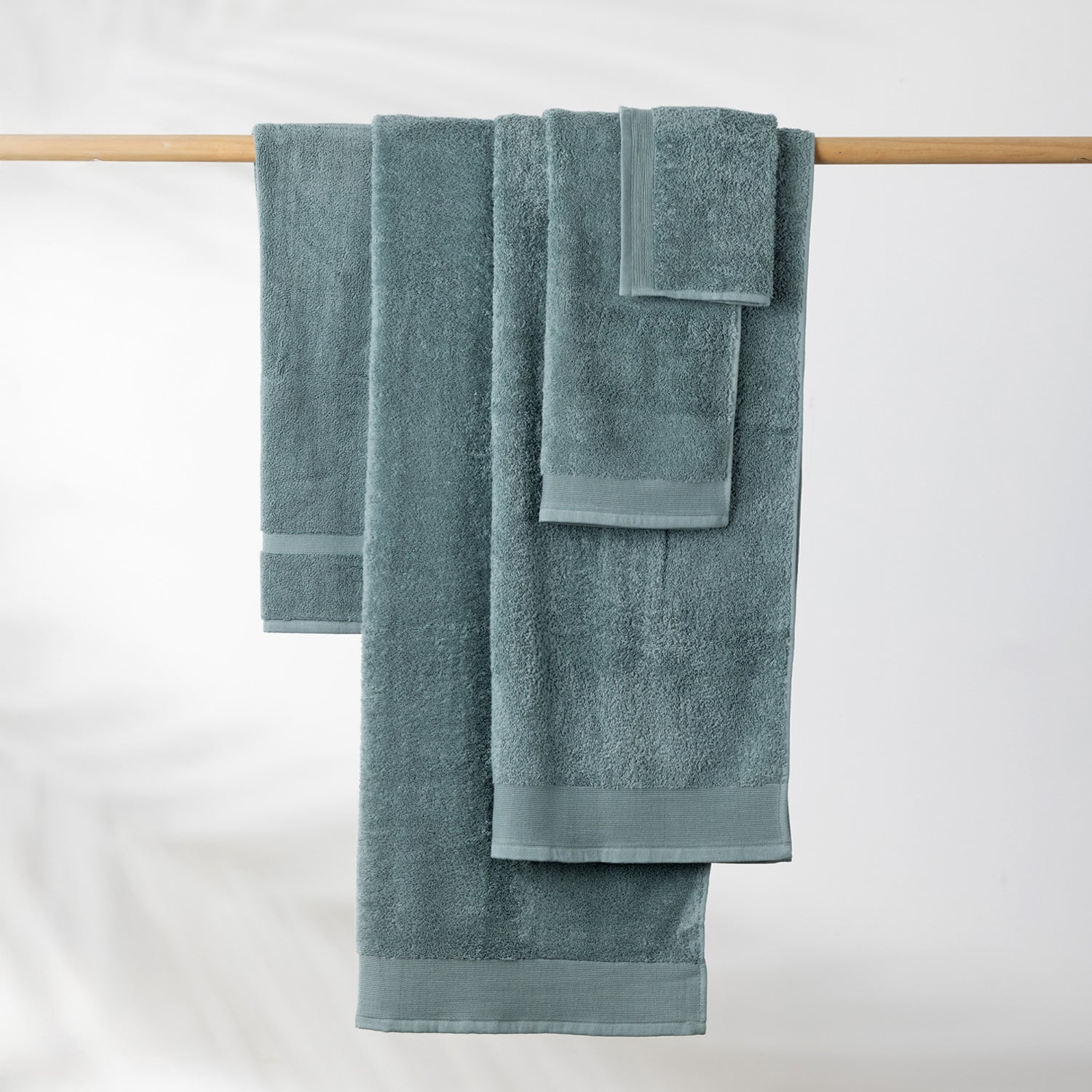 Marine Egyptian cotton towel collection including bath towel, hand towel and face cloth neatly displayed hanging over a wooden towel rail.
