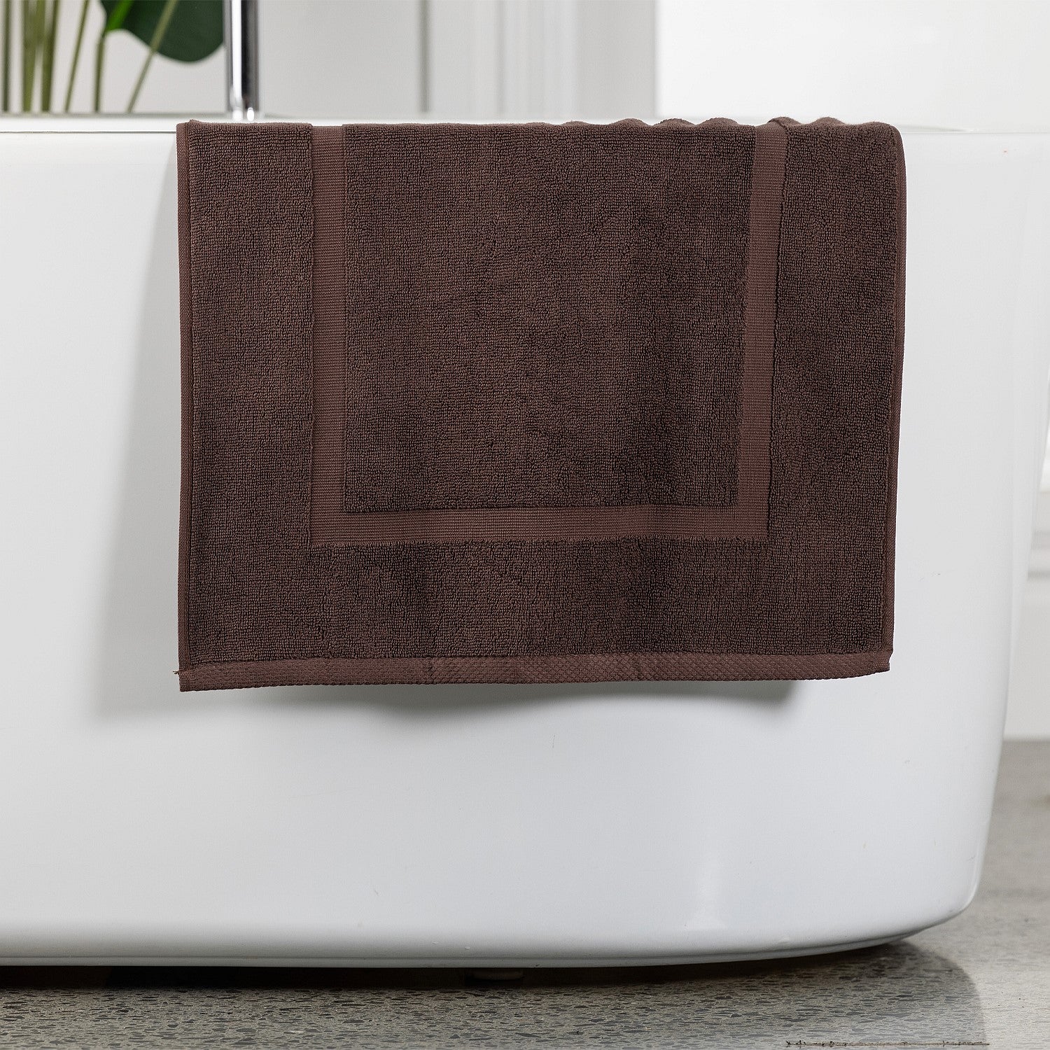 Brown bath mat hanging over bath tub