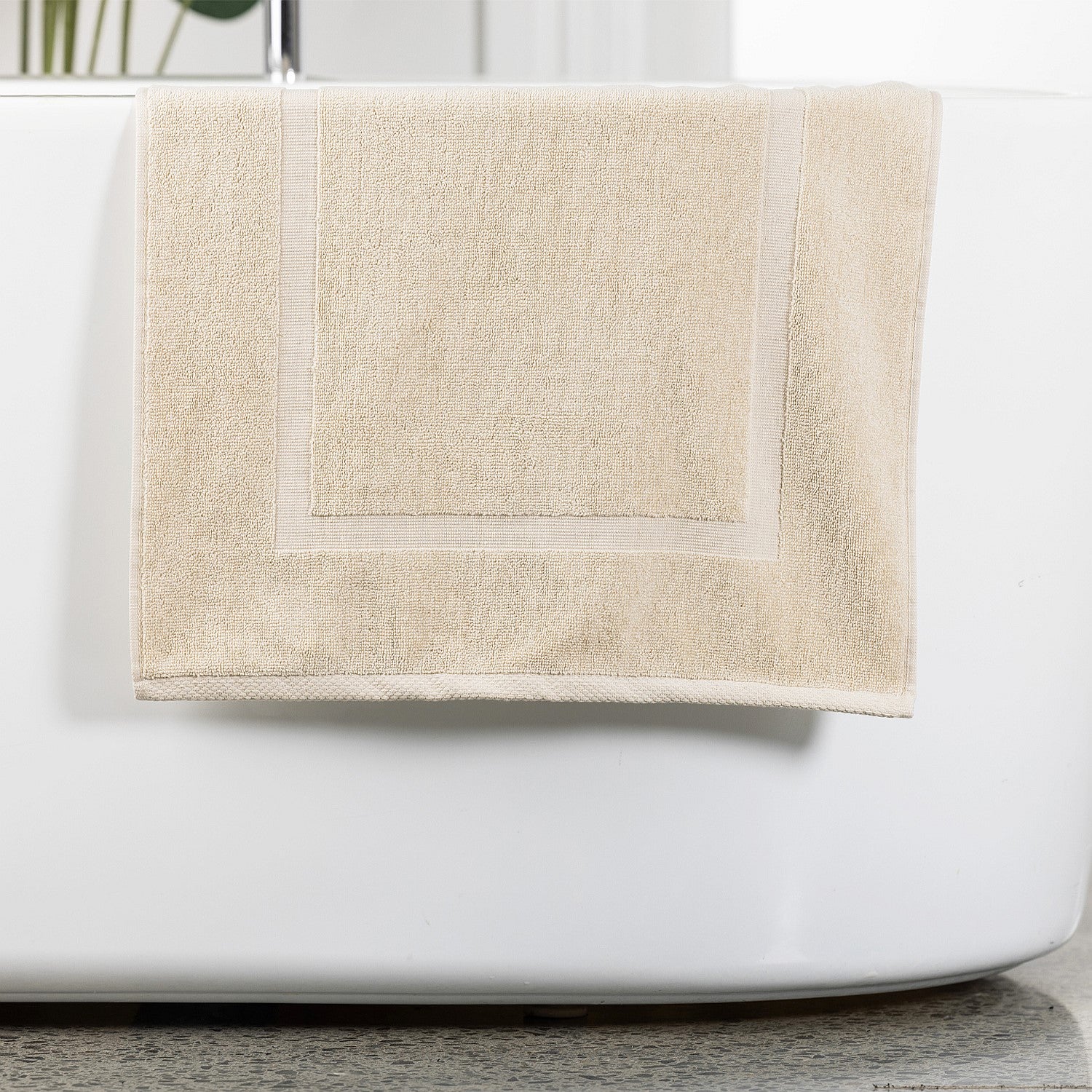 Cream bath mat hanging over bath tub