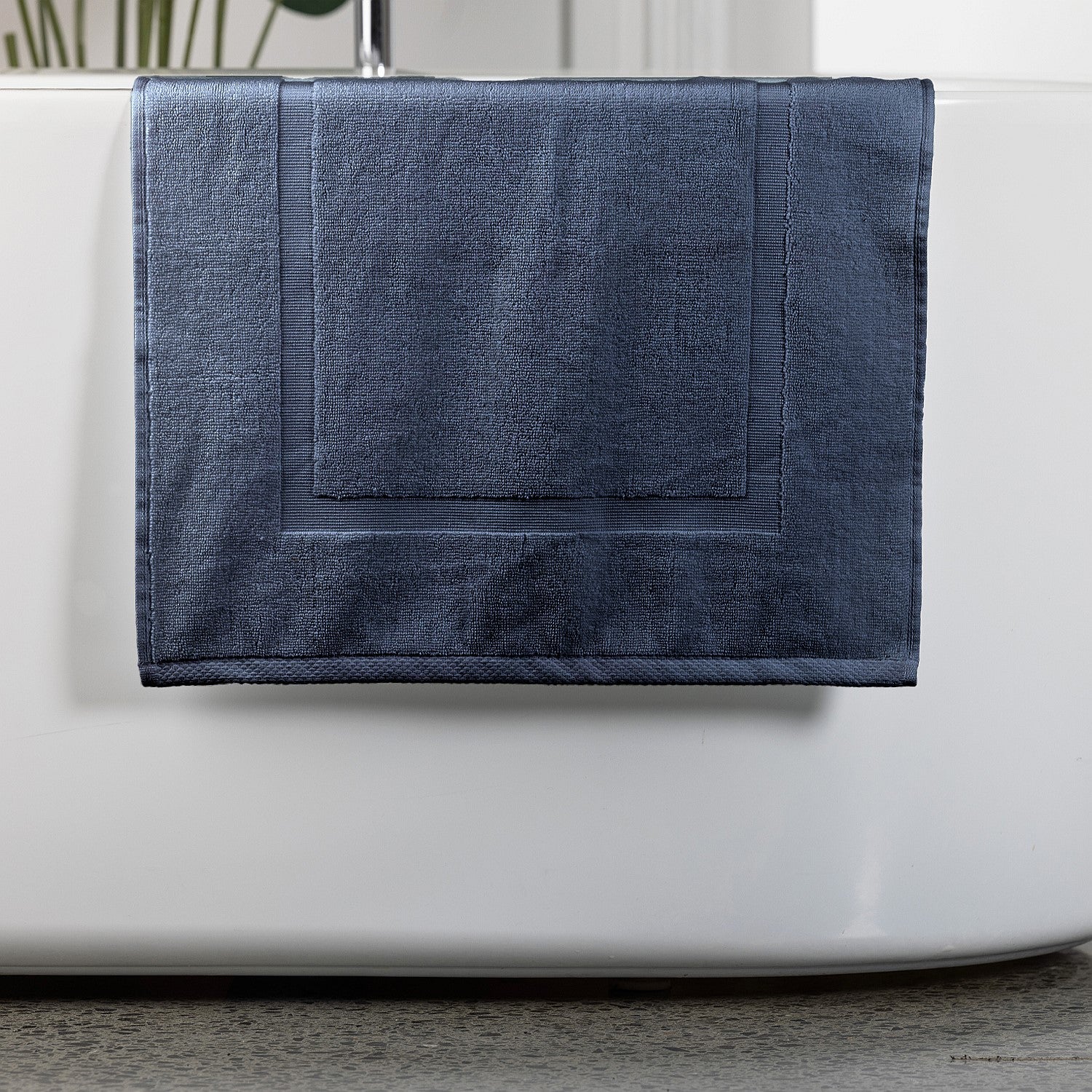 Denim bath mat hanging over bath tub