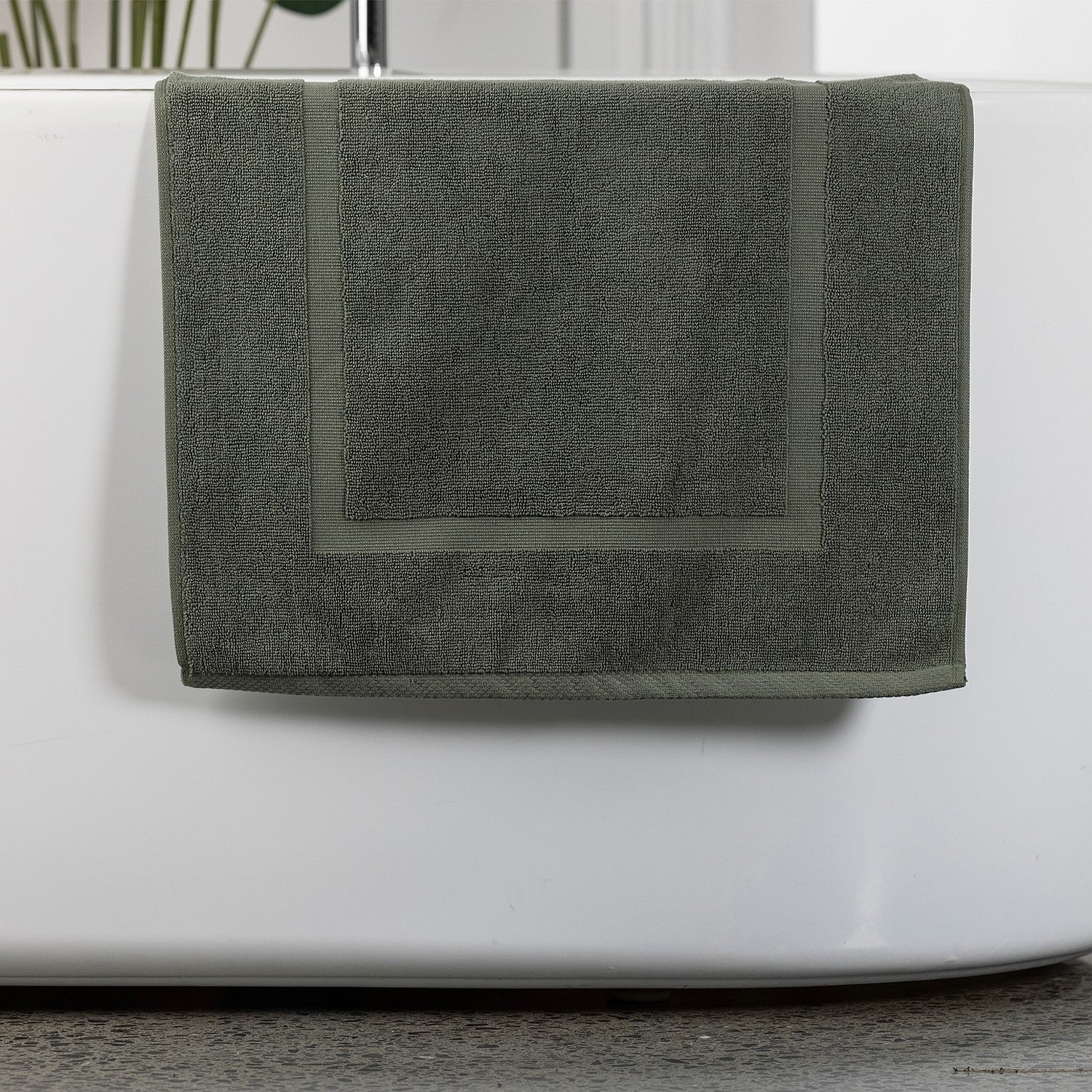 Khaki bath mat hanging over bath tub