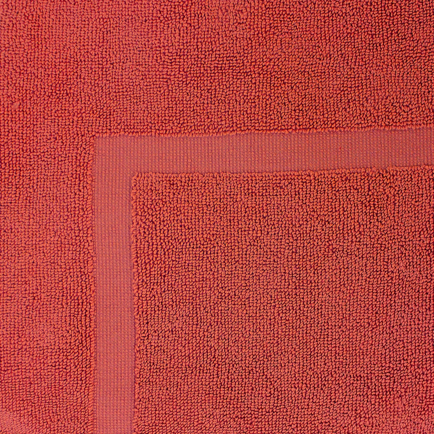 Close-up of a Deep Coral towel featuring a soft textured pile and classic border detailing.