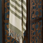 Striped green and beige throw draped over a decorative wooden screen.