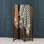 Decorative screen with striped throws against a dark blue paneled wall.