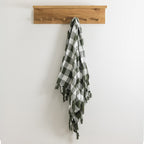 Wooden coat rack with a plaid throw on a white wall