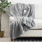 Gray heated blanket on a white couch with a plant in the background