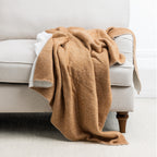 Brown throw draped over a beige armchair on a light gray background