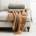 Brown throw draped over a beige armchair in a cozy living room setting.