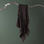 Home Co. Tilly Throw in Charcoal draped over a natural driftwood branch, showcasing the textured woven finish and tassel edging.