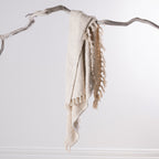 Home Co. Mateo Throw in Natural draped over a natural driftwood branch, highlighting the textured weave and tassel detail.