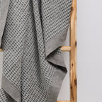 A close-up of the cotton waffle throw highlights its richly textured weave and classic woven border, adding timeless style and inviting texture to any space.