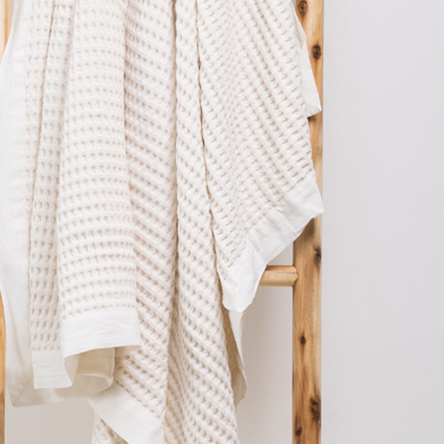 A close-up of the cotton waffle throw highlights its richly textured weave and classic woven border, adding timeless style and inviting texture to any space.