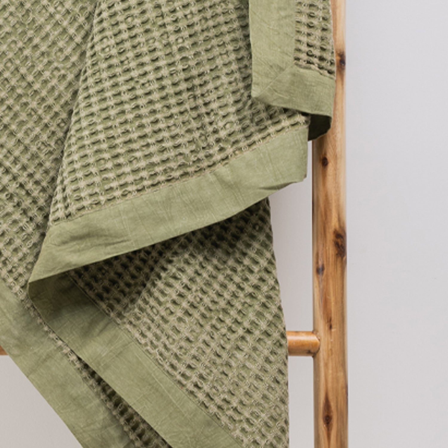 A close-up of the cotton waffle throw highlights its richly textured weave and classic woven border, adding timeless style and inviting texture to any space.