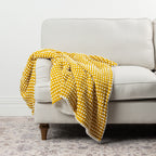 Home Co. Aiden Throw in Mustard featuring a raised white dot pattern and soft sherpa reverse, draped over a neutral sofa.