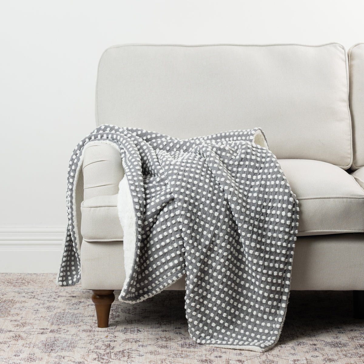 Home Co. Aiden Throw in Silver featuring a raised white dot pattern and soft sherpa reverse, styled over a neutral sofa.