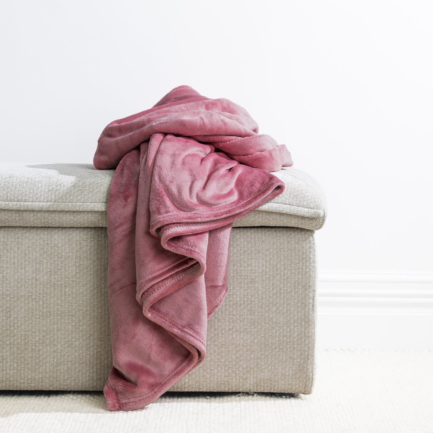 Blush: Home Co. Fraser Throw in blush pink, casually draped over a neutral upholstered ottoman.
