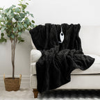 Black plush electric throw draped over a white sofa with its controller visible.
