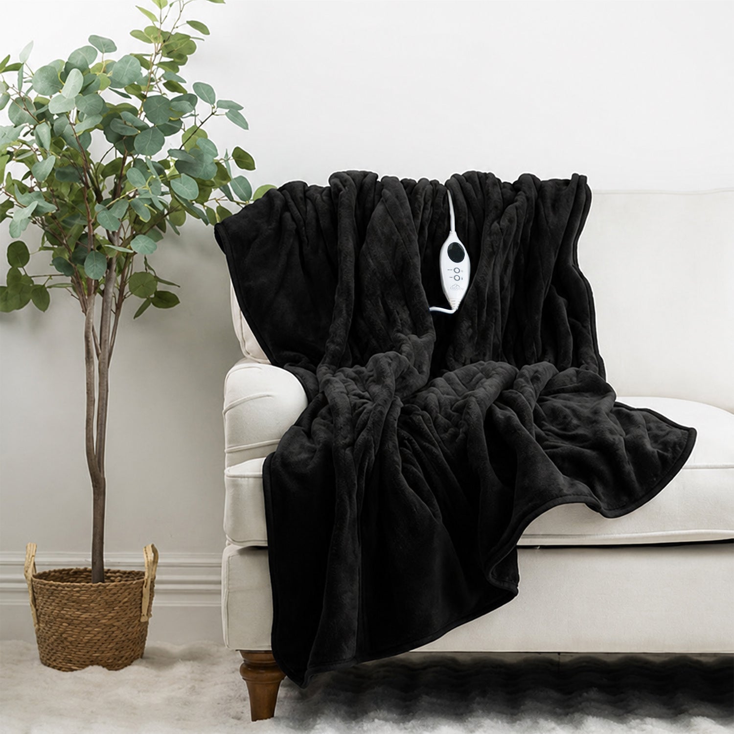 Black plush electric throw draped over a white sofa with its controller visible.