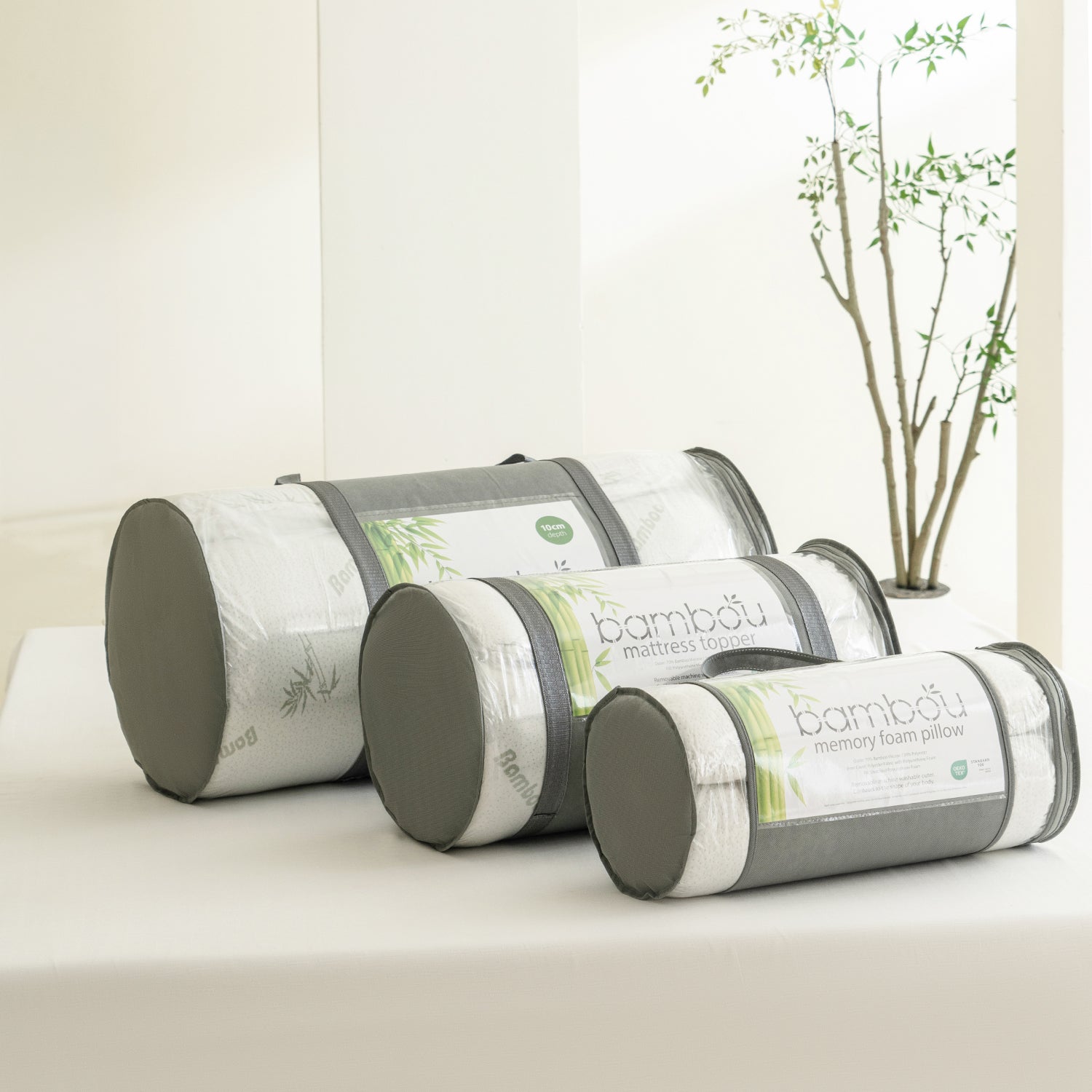 Bambou memory foam topper and pillow range packed in matching carry bags, displayed together on a tabletop to showcase the coordinated sleep collection.