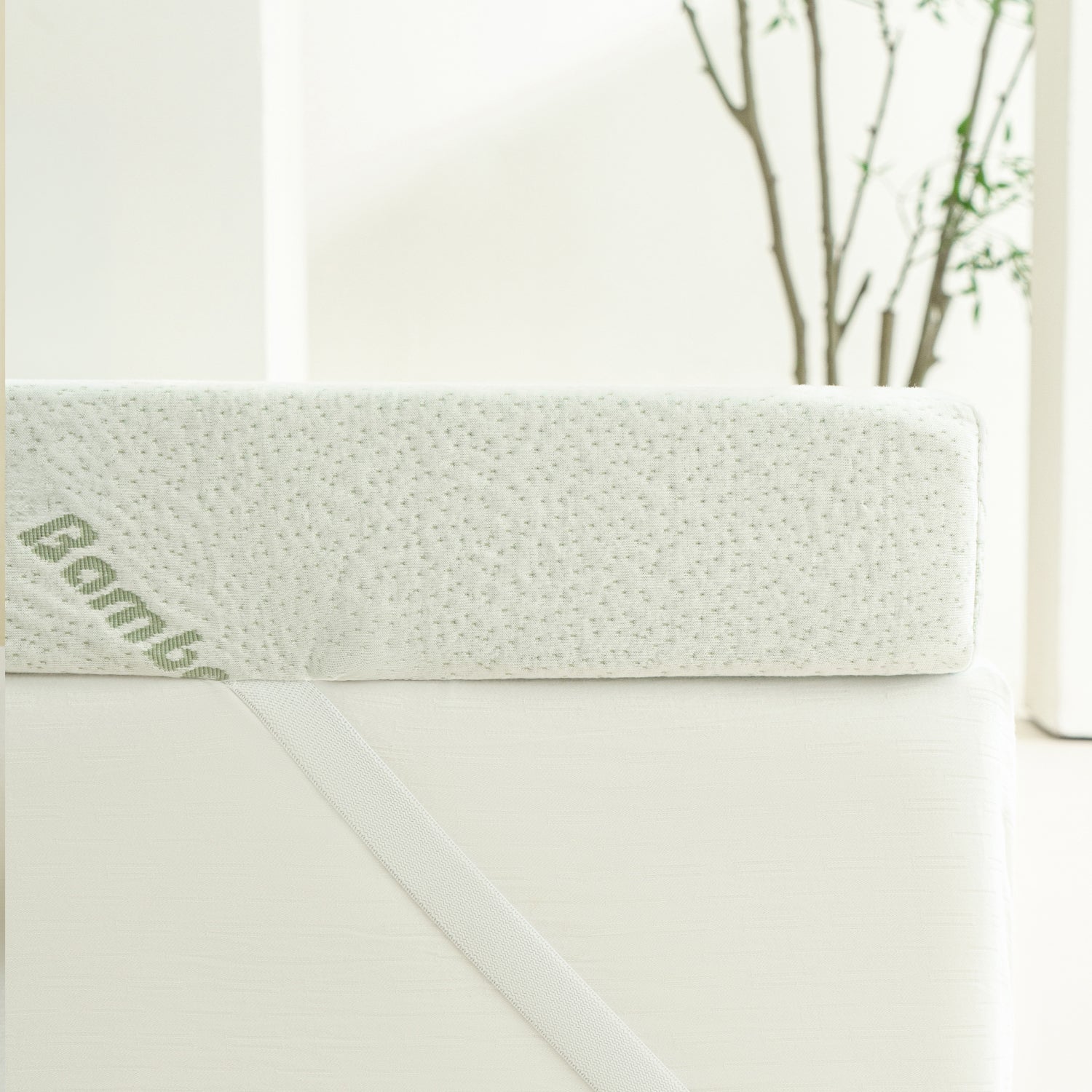Side profile of the Bambou 10cm Memory Foam Mattress Topper secured to a mattress with an elastic corner strap, highlighting the topper's thickness and bamboo-patterned cover.