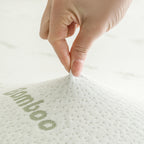 Close-up of a hand pinching the bamboo-blend cover of the Bambou Memory Foam Mattress Topper, highlighting the soft textured fabric and bamboo-patterned design.