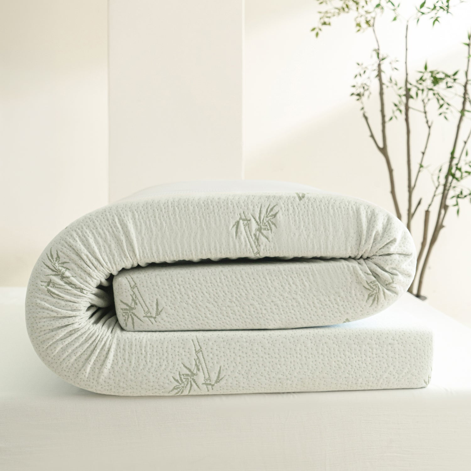 Folded Bambou 10cm Memory Foam Mattress Topper displayed on a tabletop, showing the bamboo-patterned cover and thick layered memory foam construction.