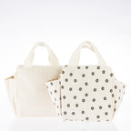 Two cream corduroy lunch totes, one plain and one with a brown daisy print, featuring carry handles and side pockets.