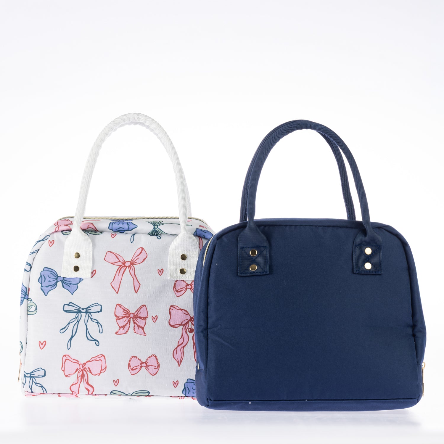 Two lunch totes with zip closures and carry handles, one featuring a colourful bow print and one in plain navy.