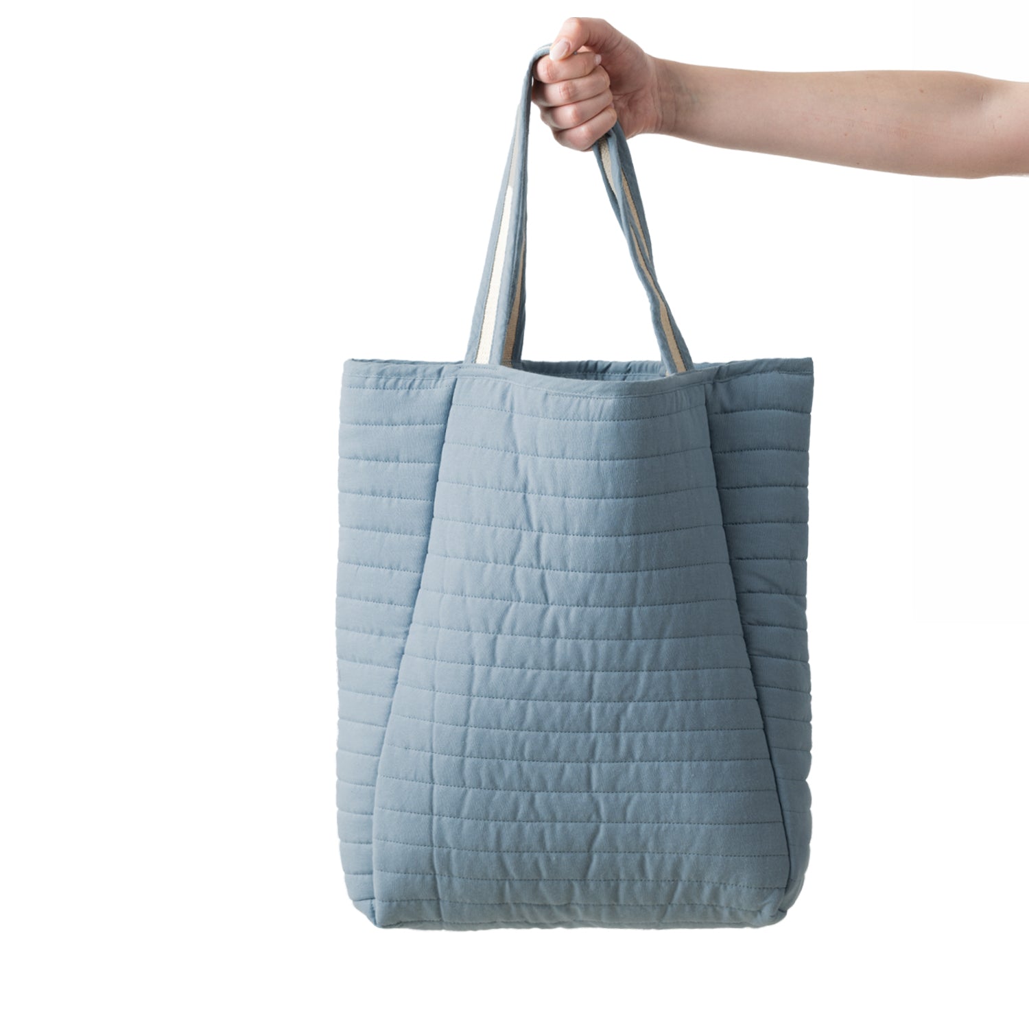 Design Plus Quinn Quilted Travel Tote in Denim, featuring a soft padded design with horizontal quilted stitching and striped carry handles.