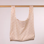 Home Co. Recycled Bottle Foldable Bag Hearts shown open and hanging on a wooden rail.
