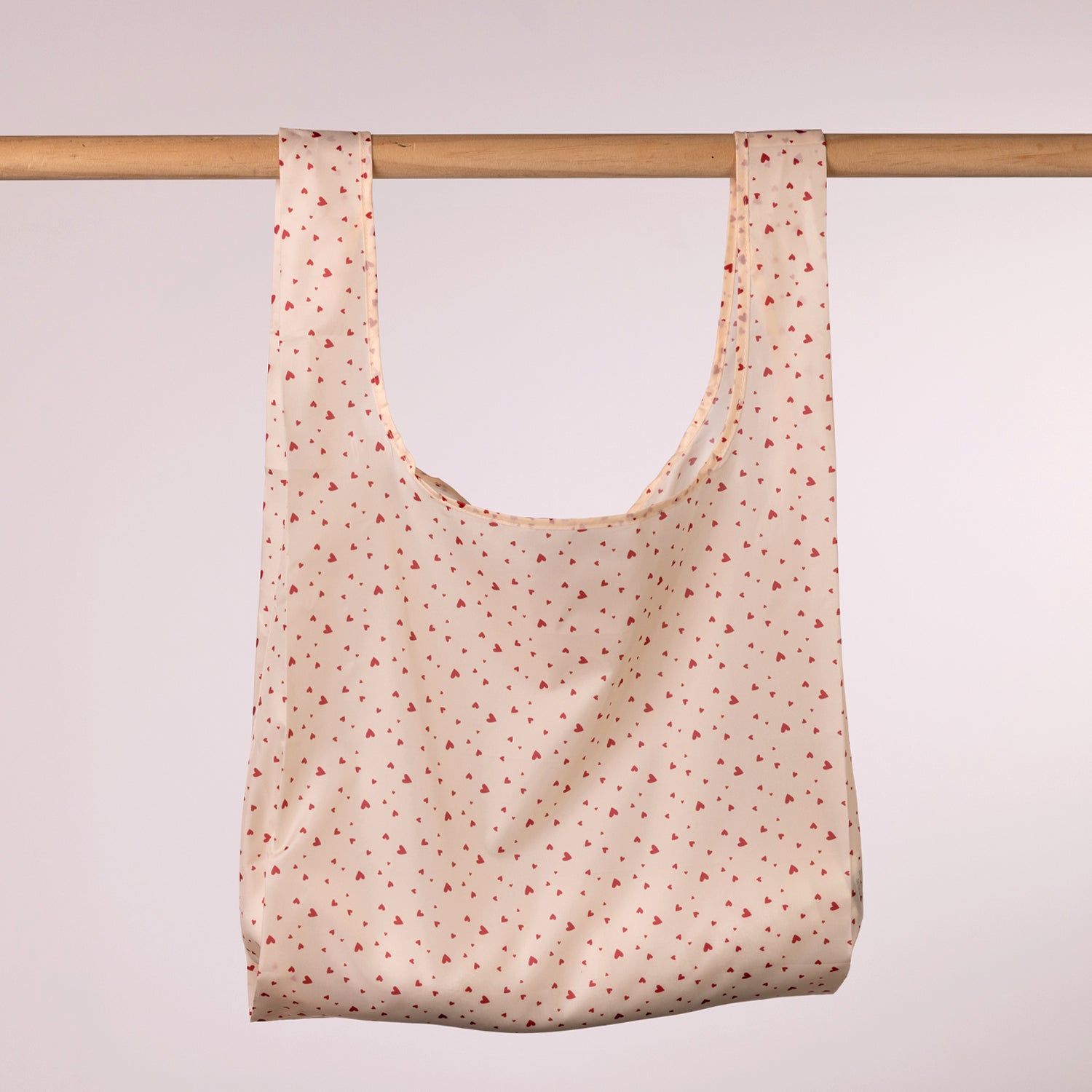 Home Co. Recycled Bottle Foldable Bag Hearts shown open and hanging on a wooden rail.