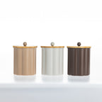 Gather Danni Canisters in Latte, White and Mocha featuring fluted cylindrical designs with natural bamboo lids and matching round knobs, displayed together in a minimalist studio setting.