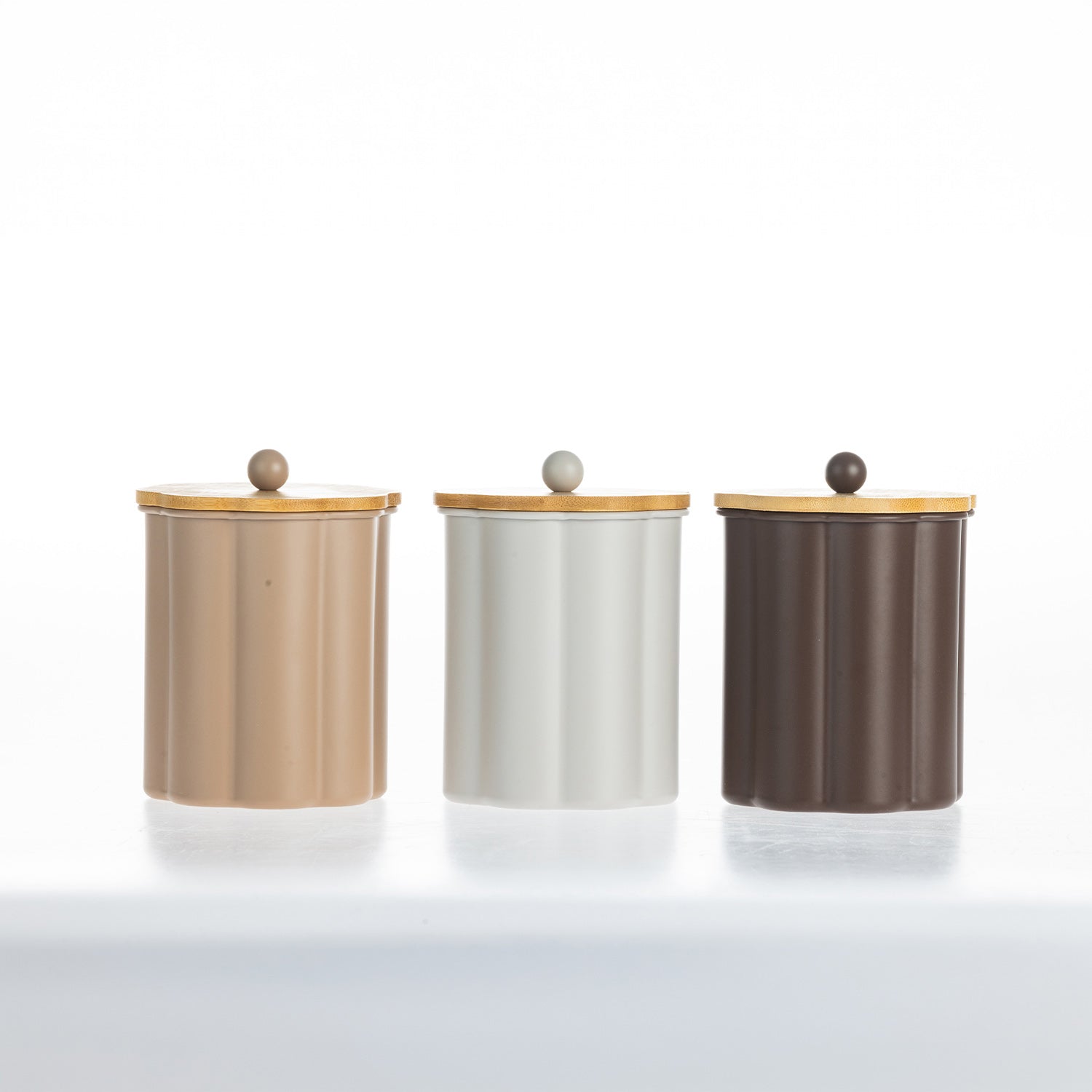 Gather Danni Canisters in Latte, White and Mocha featuring fluted cylindrical designs with natural bamboo lids and matching round knobs, displayed together in a minimalist studio setting.
