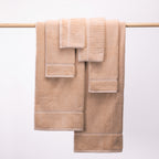 Design Plus Ivy Super Plush 650gsm Towel Pack in blush, with two bath towels, two hand towels and two face cloths displayed over a wooden rail.