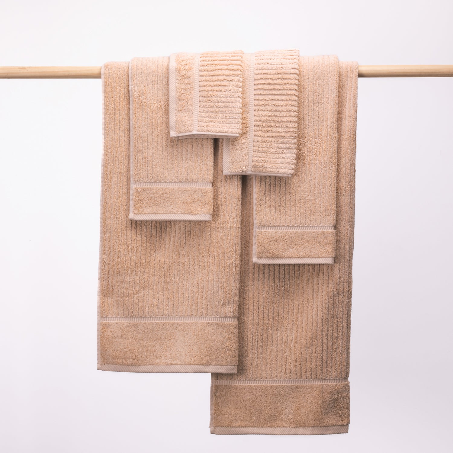 Design Plus Ivy Super Plush 650gsm Towel Pack in blush, with two bath towels, two hand towels and two face cloths displayed over a wooden rail.
