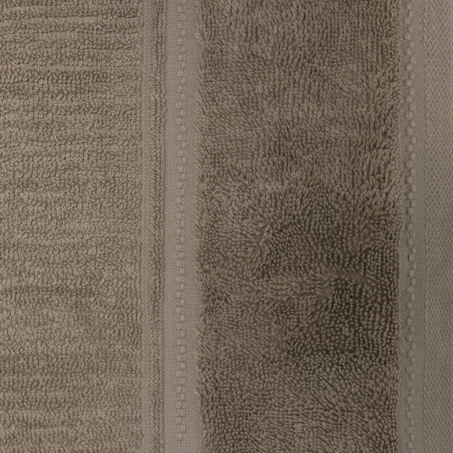 Close-up of the beige Design Plus Tia towel, showing the plush cotton loops and decorative woven border.