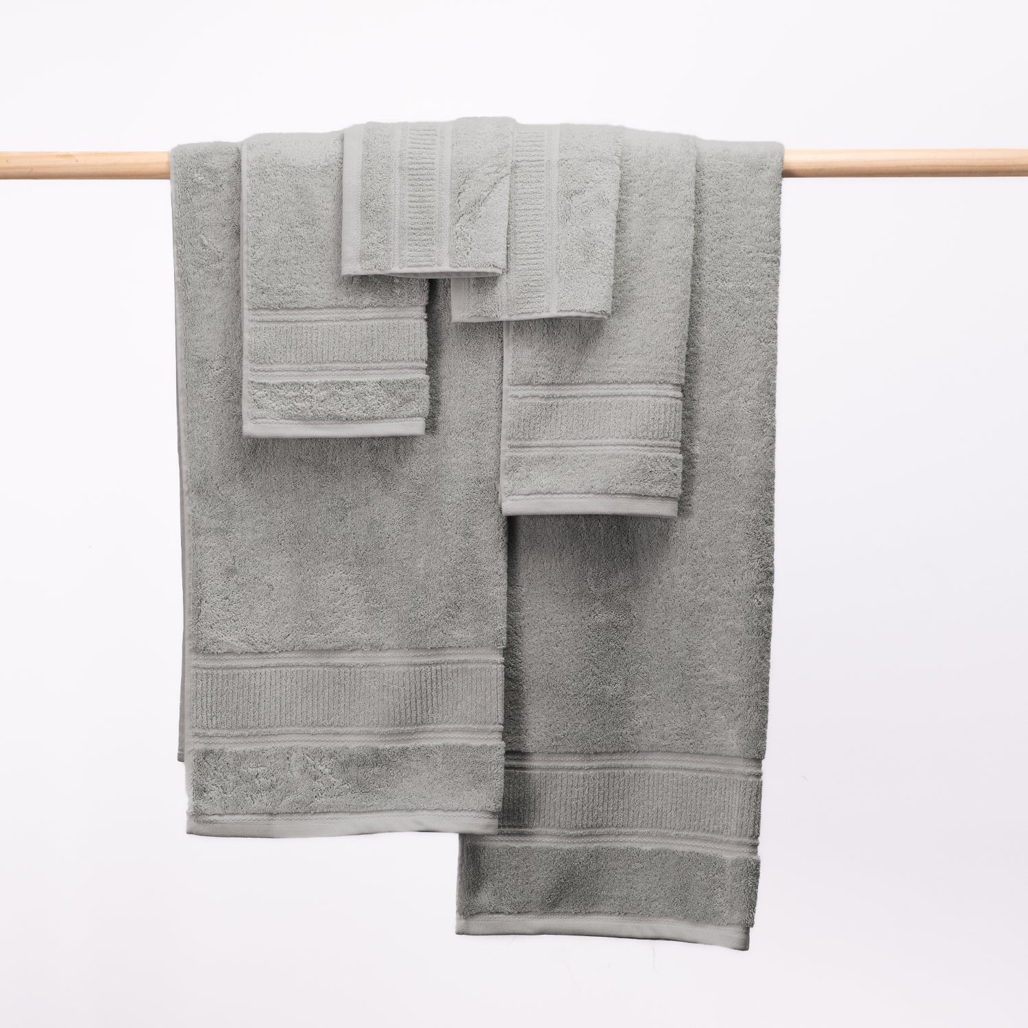 Design Plus Tia Plush 600gsm Towel Pack in silver displayed over a wooden rail.