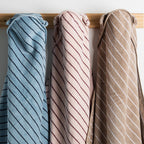 Close up of three bath hooded towels in blue, pink, and natural hanging side by side.