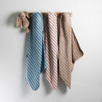 Three bath hooded towels in blue, pink, and natural hanging side by side.