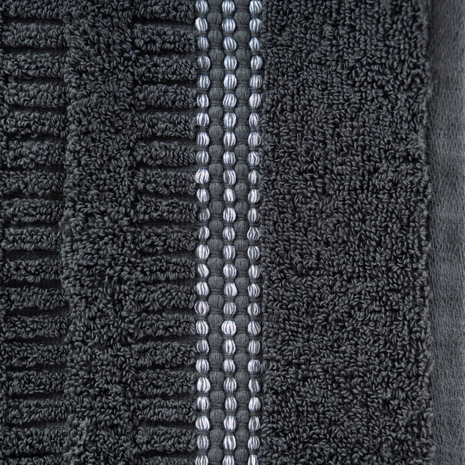 Close-up of the Home Co. Penny Self Stripe Face Cloth in coal, showing the soft textured cotton loops, raised stripe pattern and decorative border detail.